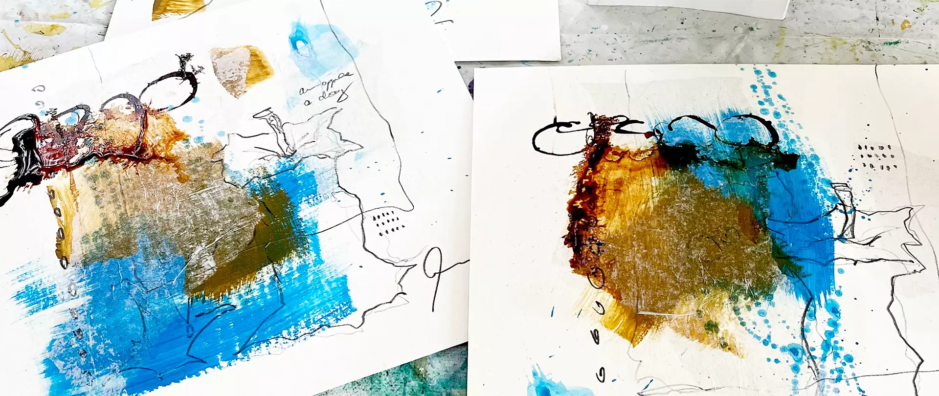 Zwei abstrakte Mixed-Media-Kunstwerke mit blauen, goldenen und braunen Farbflecken, schwarzen Linien und Skizzen auf weißem Papier erstellt von artistravel Dozentin Anita Hoerskens