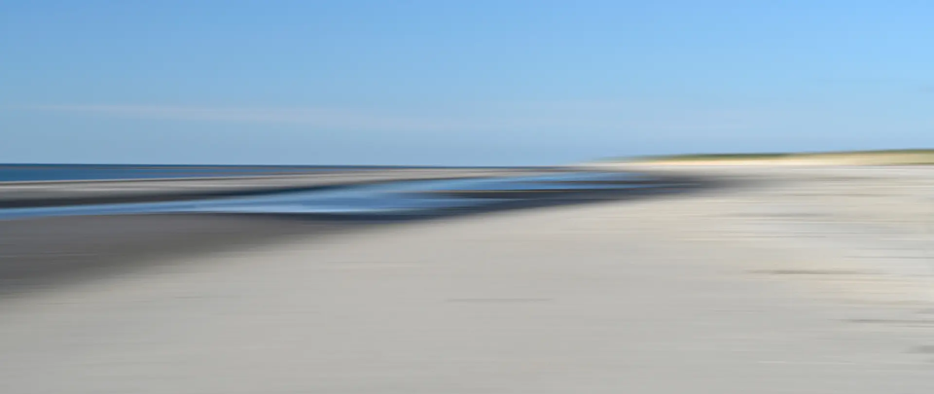 Nordseeinsel Amrum mit weitem Sandstrand und Dünenlandschaft bei klarem Himmel zum kreativen Fotografieren und Experimentieren