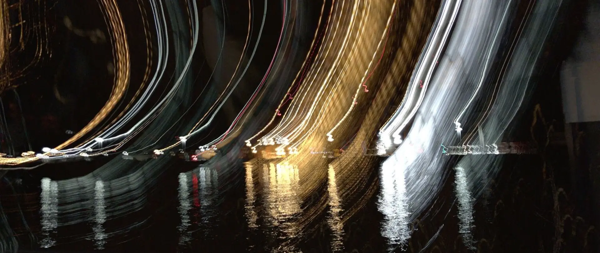 Langzeitbelichtung der Hamburger Elbkulisse mit verwischten Lichtspuren und Reflexionen auf dem Wasser bei Nacht