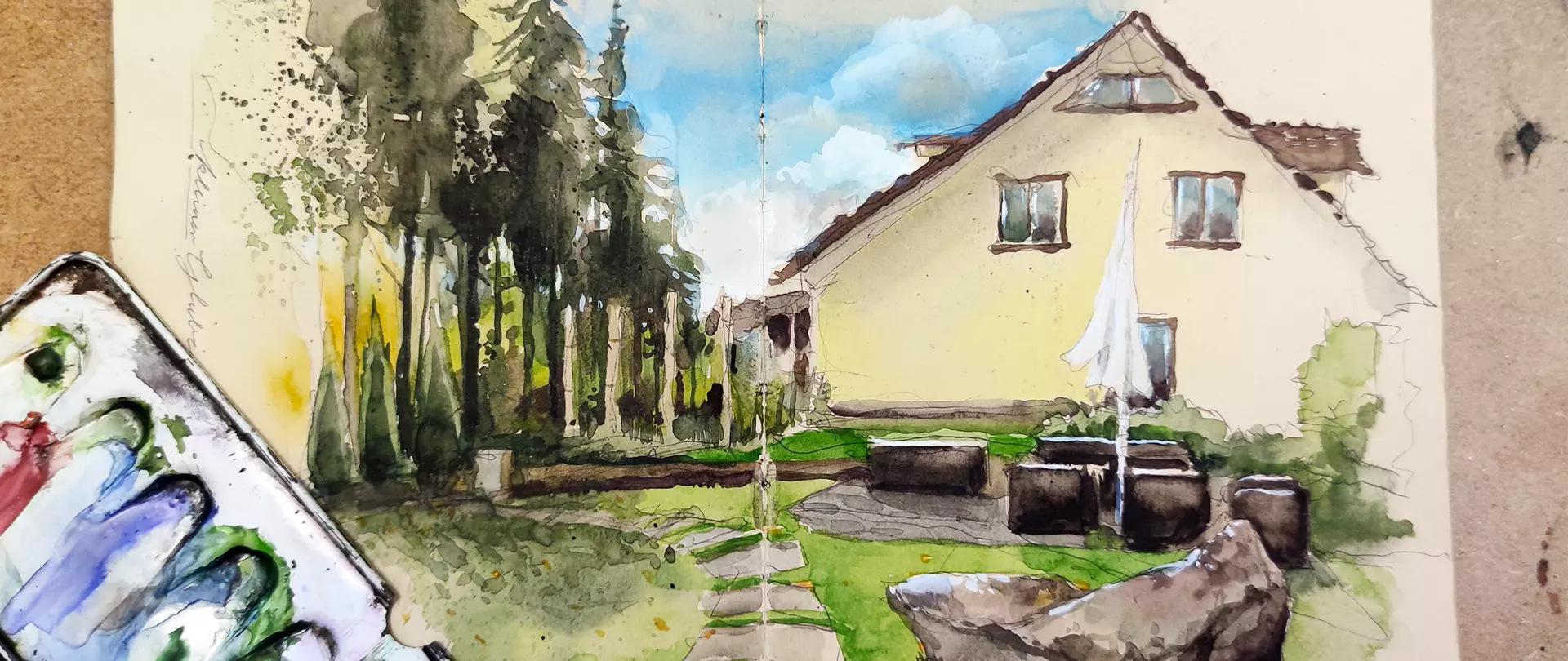 Aquarellskizze eines Hauses mit Garten und Bäumen, umgeben von Malkasten und Malutensilien, vermittelt Grundtechniken des Zeichnens und Aquarellmalens