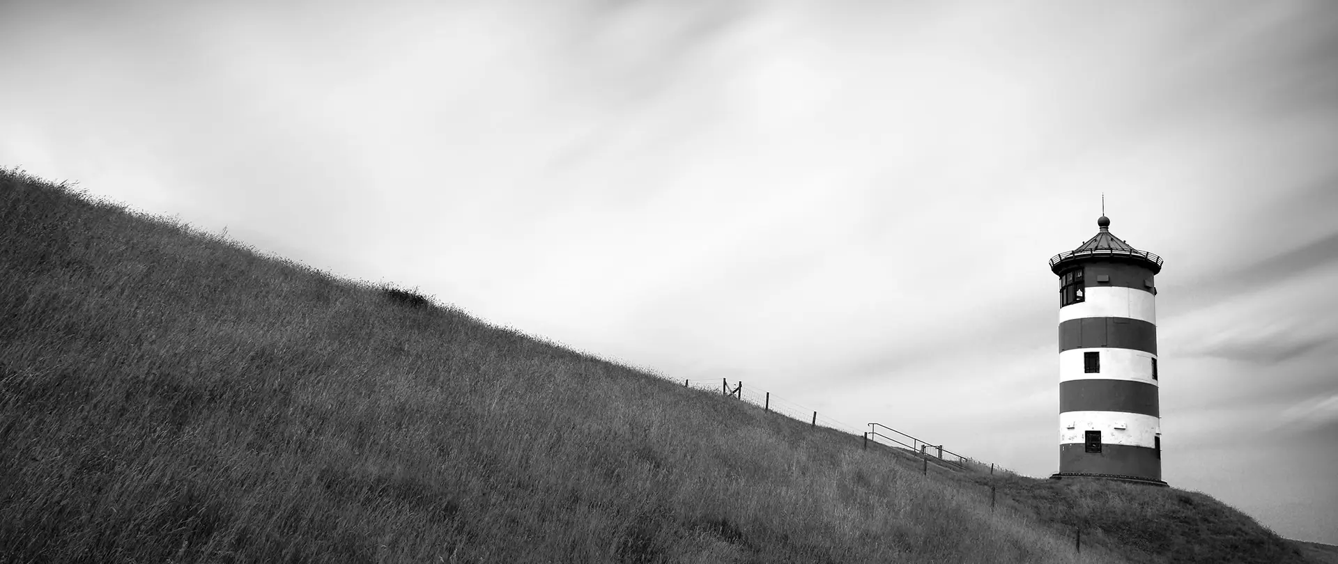 Leuchtturm auf Hügel mit weichem Licht und langzeitbelichteter Wolkenbewegung für Fine Art Fotografie