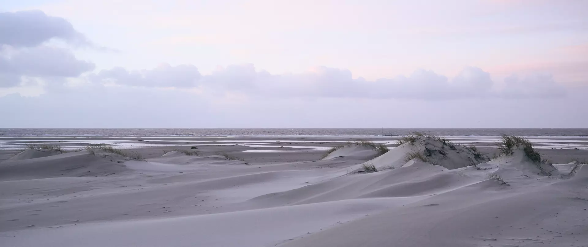 Winterliche Dünenlandschaft auf Amrum mit sanften Hügeln und ruhigem Meer im weiten, klaren Licht der Nordsee