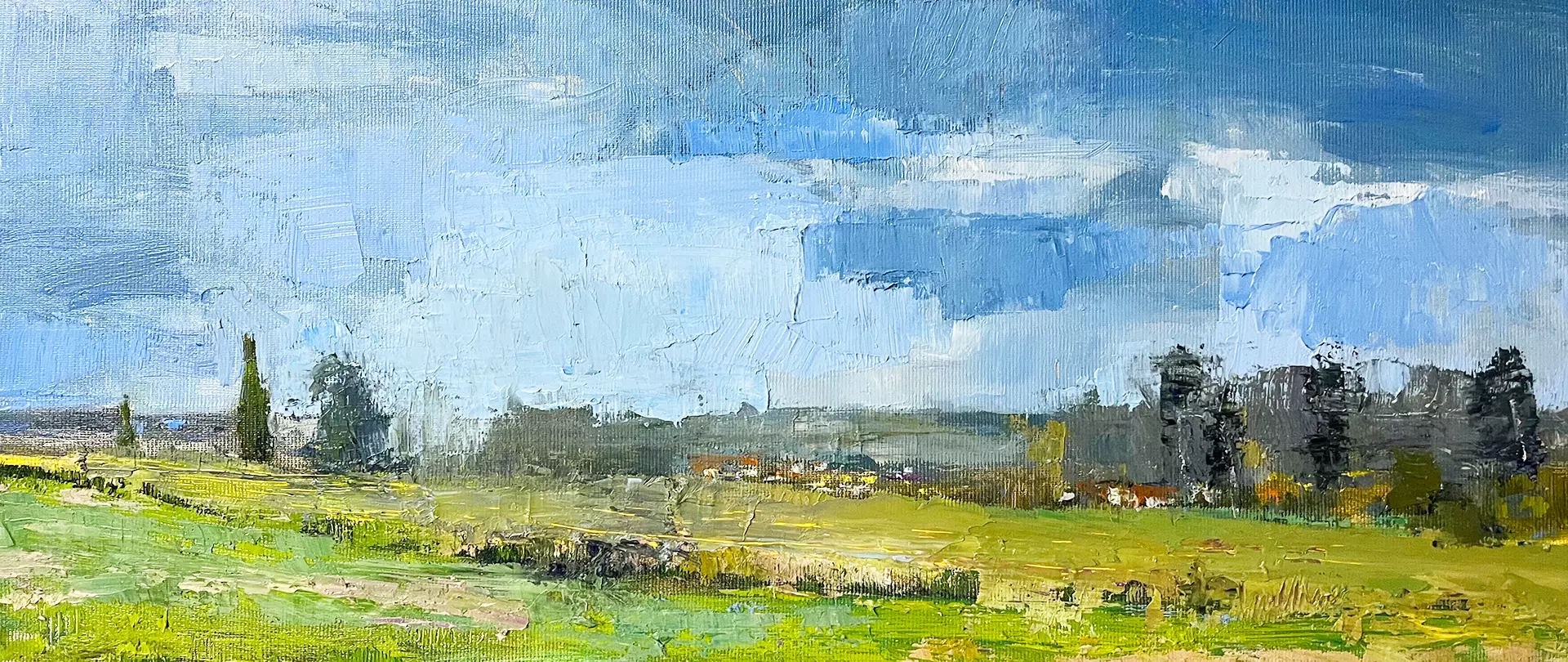 Landschaftsbild mit weitem grünem Feld im Vordergrund. Im Hintergrund sind reduzierte dunkle Formen von Bäumen und Häusern zu erkennen. Zudem lassen dunklere Flächen im Himmel eine unruhige Wetterlage vermuten.