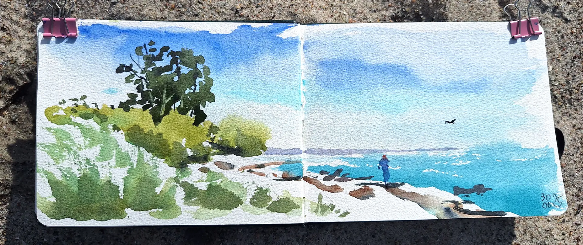 Unbenanntes Projekt Landschaftsaquarell im Skizzenbuch mit Büschen, Wasser, blauem Himmel und einer stehenden Person am Meer, locker und spontan gemalt