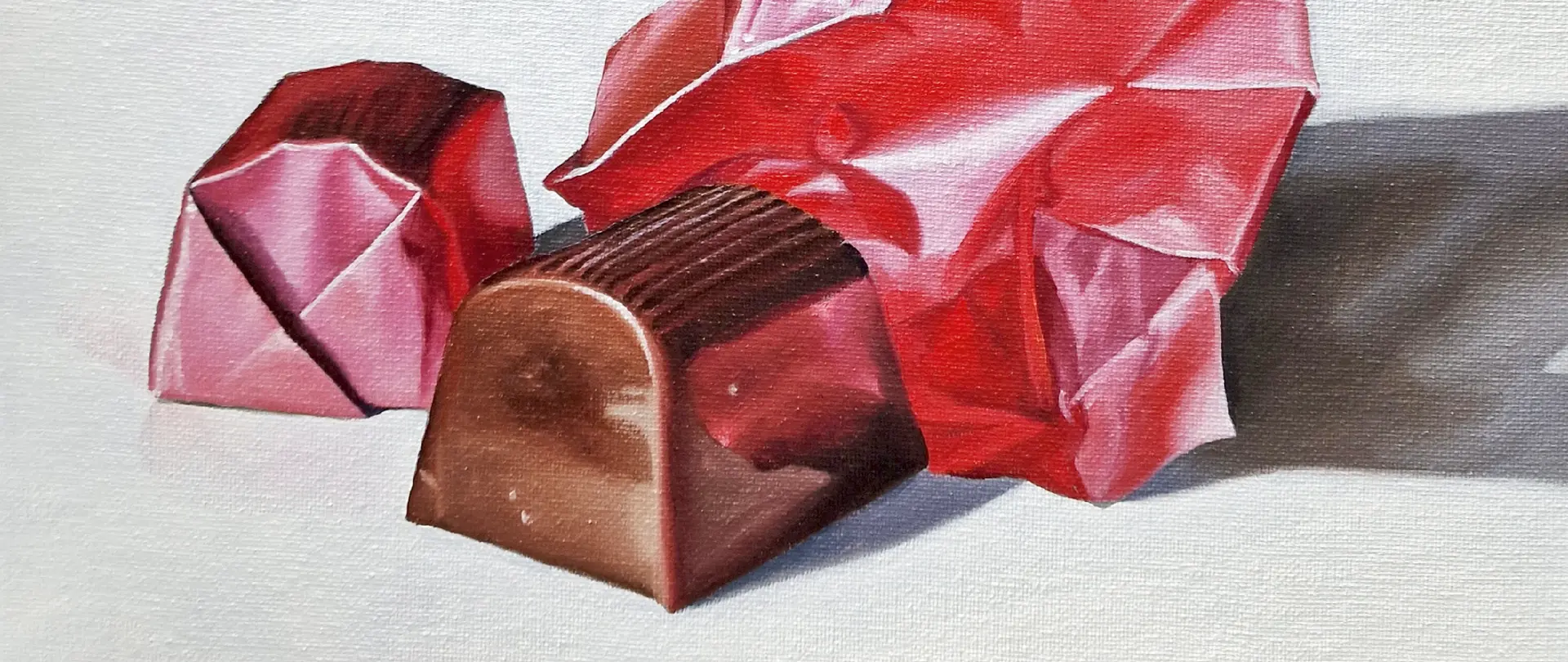 Realistisch gemalte Schokoladenpraline in rotem Papier als Beispiel für fein detaillierte Ölmalerei
