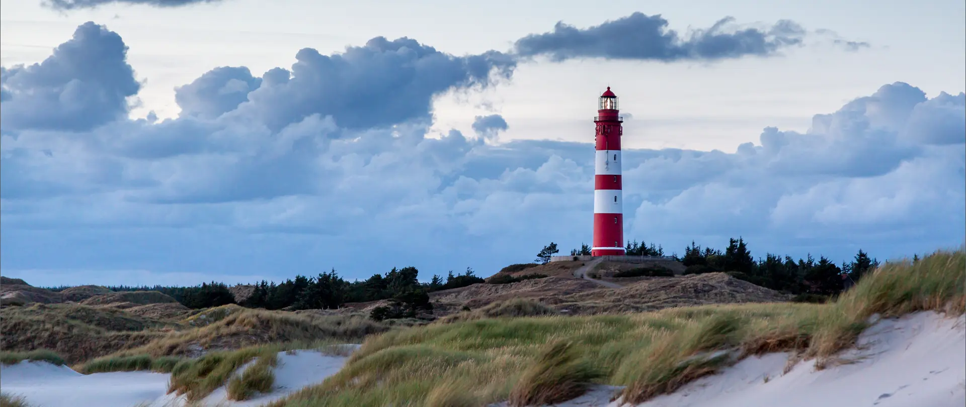 Leuchtturm auf Amrum in reizvoller Dünenlandschaft mit bewölktem Himmel als Motiv für Natur- und Landschaftsfotografie-Kurs