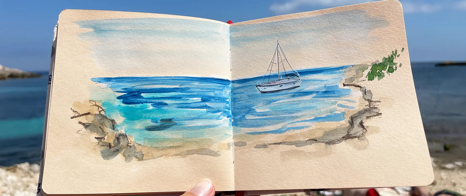 Reiseskizzenbuch Prerow – Zeichnen und aquarellieren an der atemberaubenden Ostsee Aquarell-Skizze eines Segelbootes auf der Ostsee mit Felsen im Vordergrund, gemalt in einem Reiseskizzenbuch am Strand von Prerow