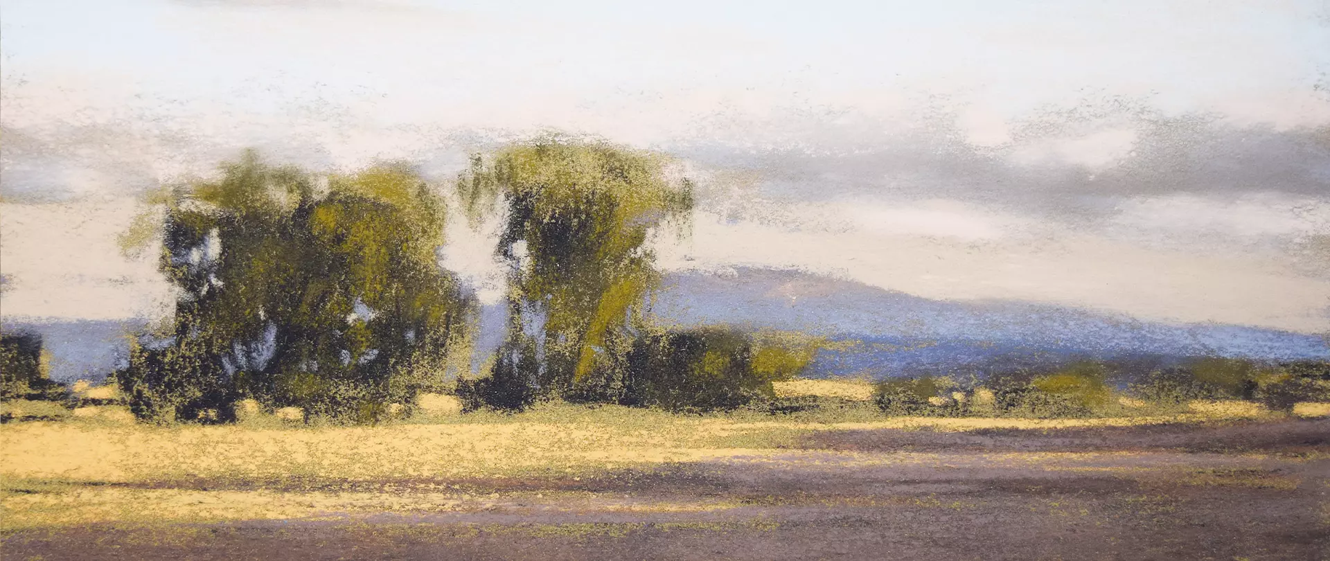 Pastellzeichnung einer Landschaft mit Bäumen im Vordergrund, einem Feld und Bergen im Hintergrund unter bewölktem Himmel erstellt von artistravel Dozentin Martina Zingler