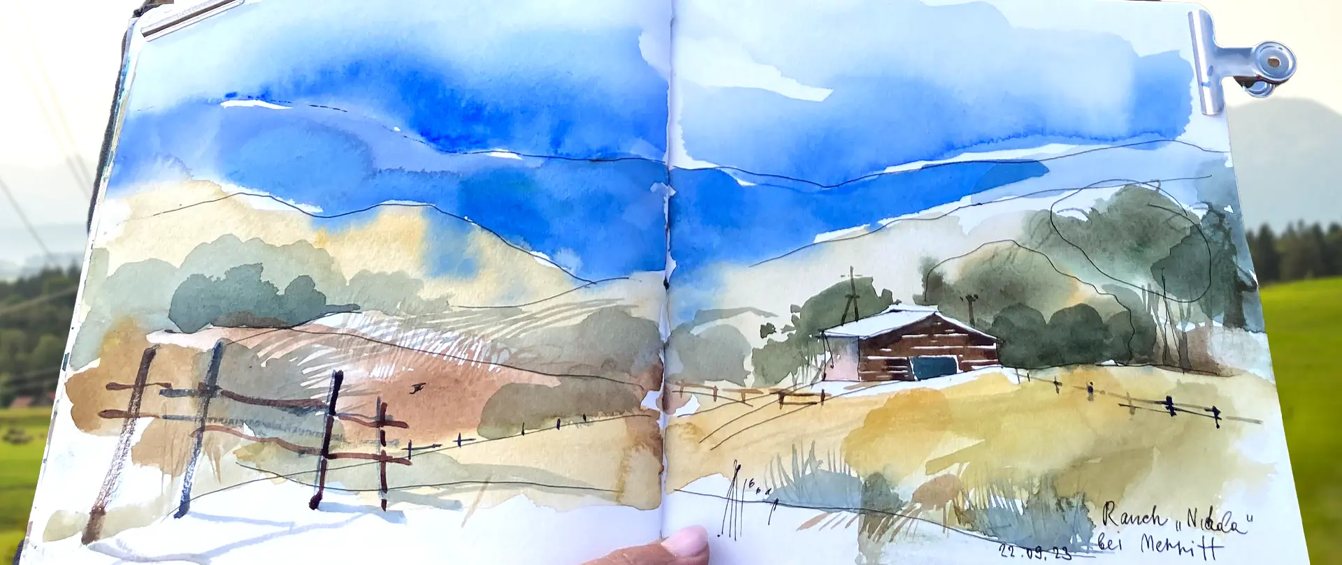 Aquarellskizze einer Berglandschaft mit weitem Tal, Nebelstimmung, Holzhütte und Zaun unter blauem Himmel, vermittelt Atmosphäre des Berglandschaftskurses