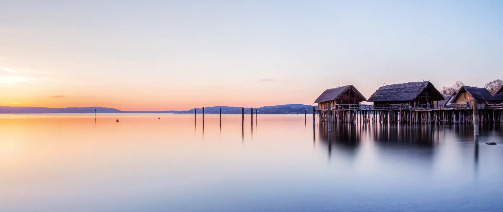 Stimmungsvolle Fine Art Fotografie mit Seehäusern auf Stelzen und ruhigem Bodensee bei sanftem Sonnenuntergang am westlichen Ufer