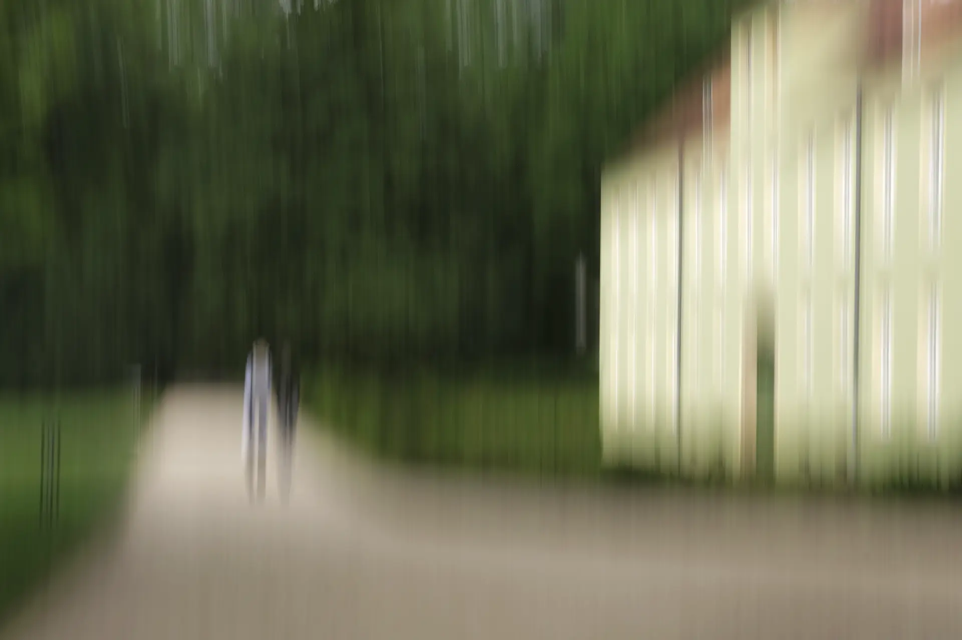 Verschwommenes Foto (ICM) eines Weges mit zwei Personen im Park vor einem historischen Gebäude in Potsdam, umgeben von Grün und Schlosskulisse