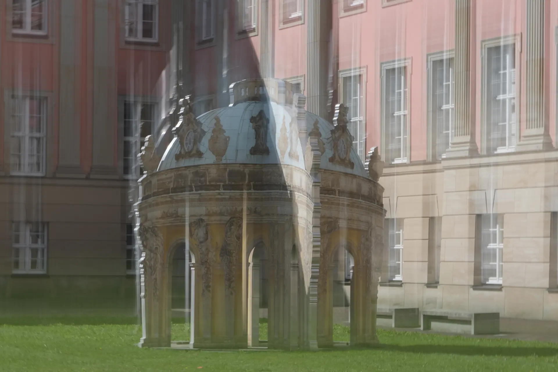 Spiegelung eines historischen Pavillons vor klassizistischen Potsdamer Schlossfenstern in einer grünen Parkanlage bei sonnigem Wetter