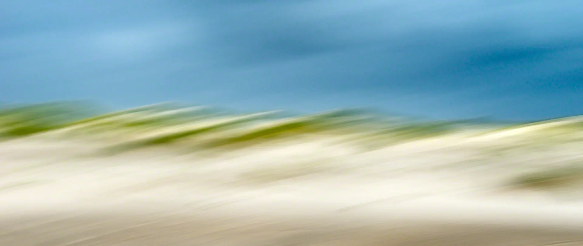 Abstrakte, verwischte Aufnahme der Dünen- und Strandlandschaft der Nordseeinsel Amrum als kreative Inspiration für malerische Fotografie