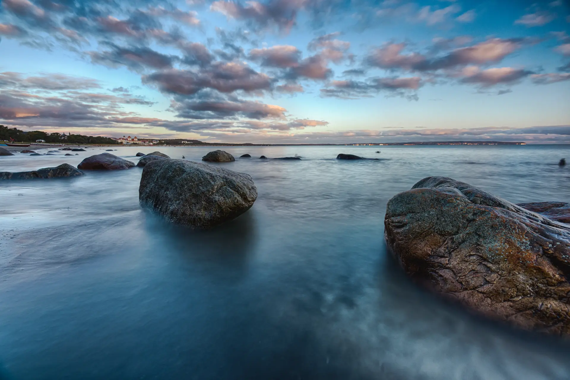 Felsen in der Ostsee bei ruhigem Wasser unter stimmungsvoller Wolkenformation bei Sonnenuntergang auf der Insel Rügen