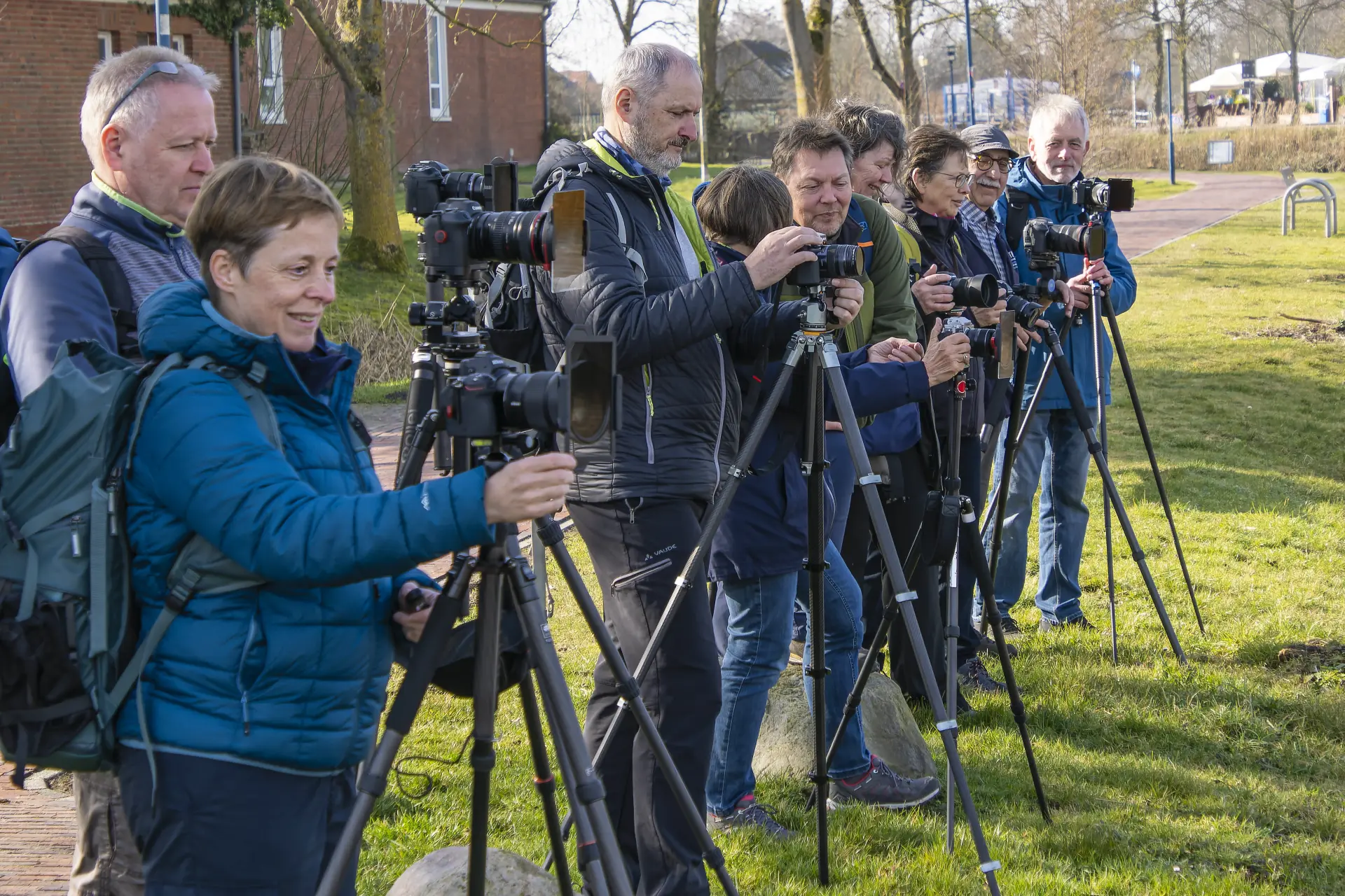 Gruppe von Fotografen bei einem Outdoor-Kurs, die mit Kameras und Stativen Langzeitbelichtungen von Landschaft und Wasser im weichen Licht aufnehmen