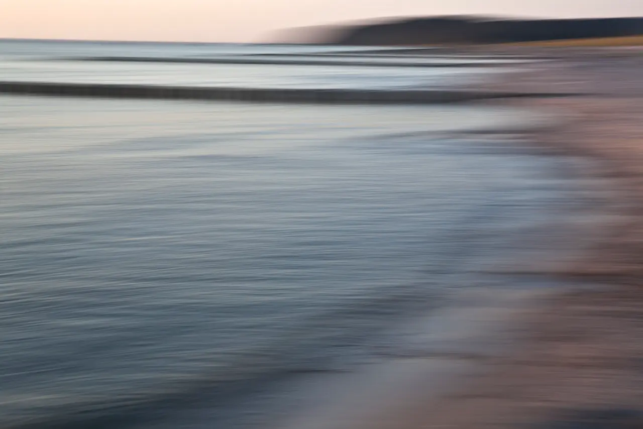 Abstrakte Strandaufnahme mit verschwommenem Wasser und Horizont, die die kreative Technik des Fotografierens als künstlerisches Mittel mit Licht zeigt