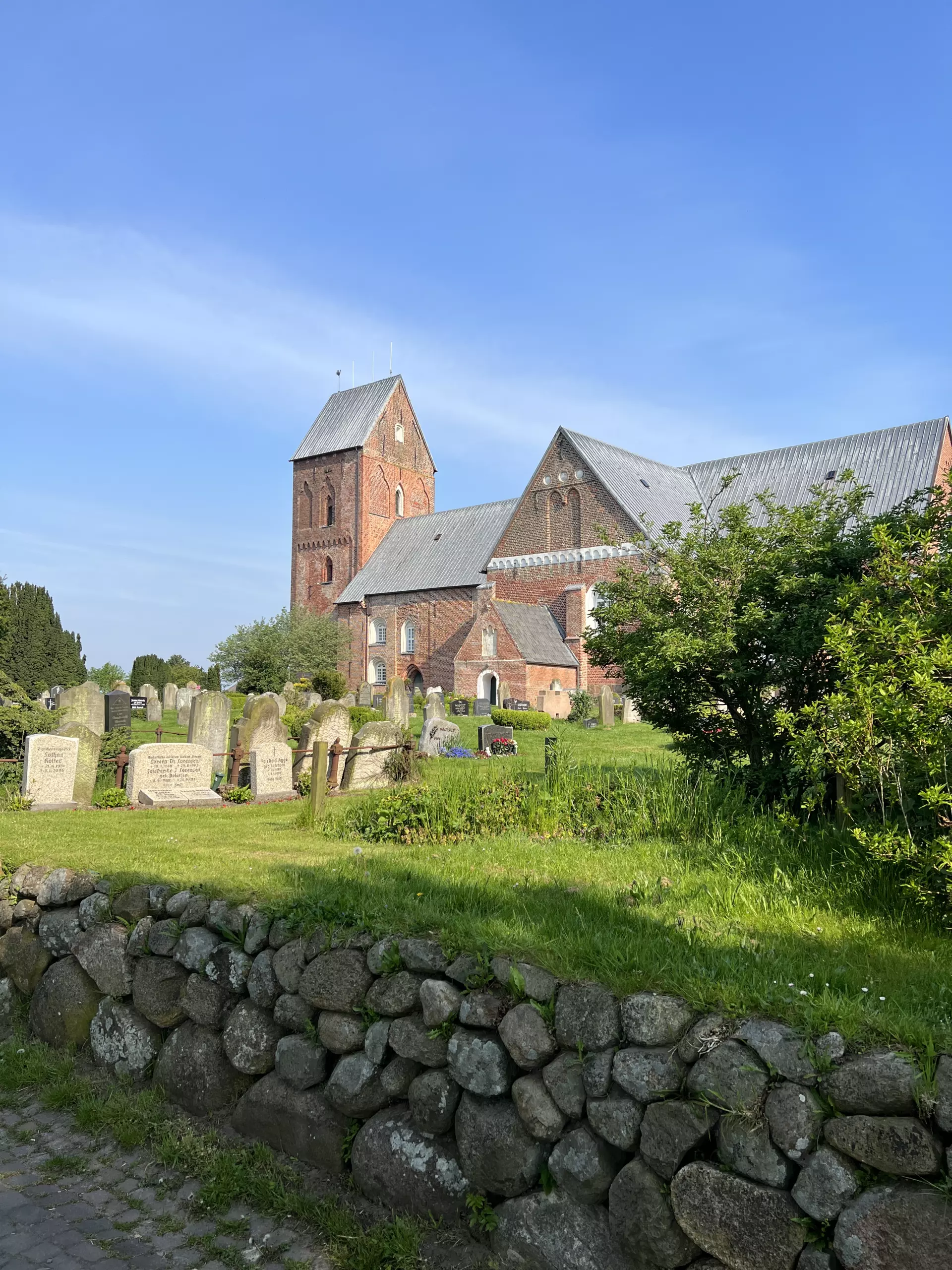 Föhr Backsteinkirche mit Friedhof und Steinmauer bei sonnigem Himmel auf der Insel Föhr