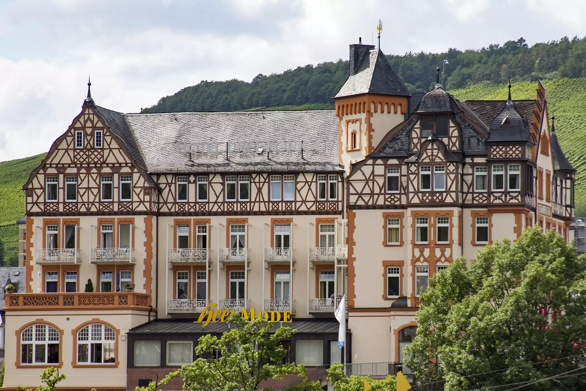 Fachwerkhaus in der Moselregion Fachwerkhaus mit Turm und Weinberg im Hintergrund in der Moselregion bei bewölktem Himmel