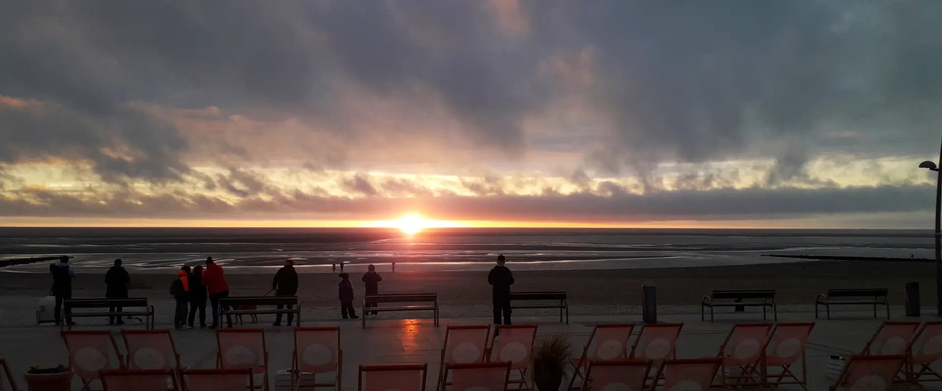 Sonnenuntergang am Strand von Borkum Sonnenuntergang am Strand von Borkum mit Menschen und leeren Liegestühlen im Vordergrund
