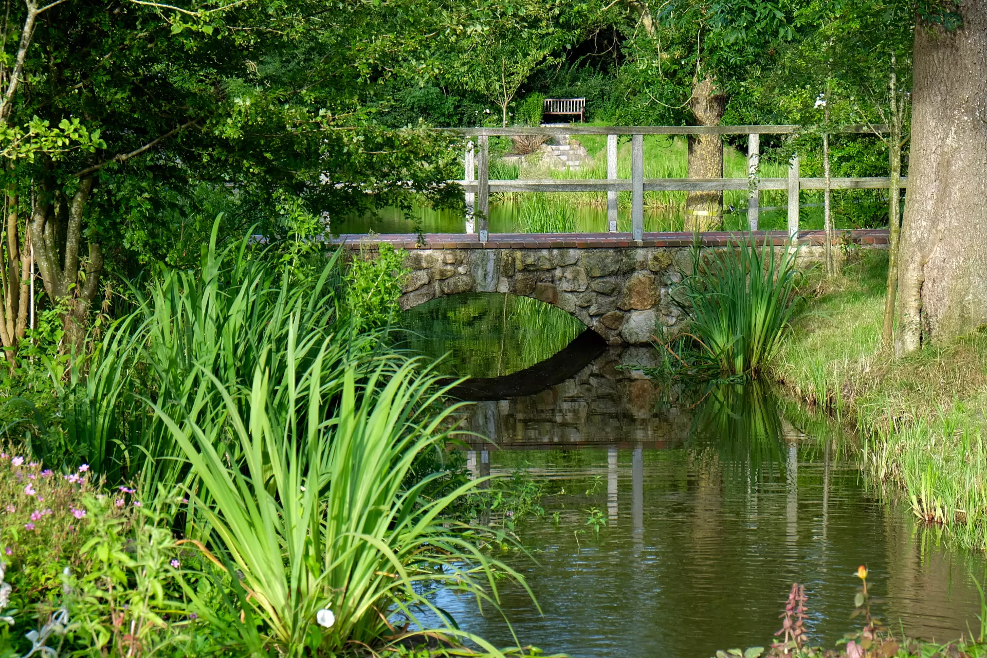 Kunze Hof Steinbrücke über einen schmalen Fluss mit grüner Ufervegetation und Bäumen im Wattenmeer