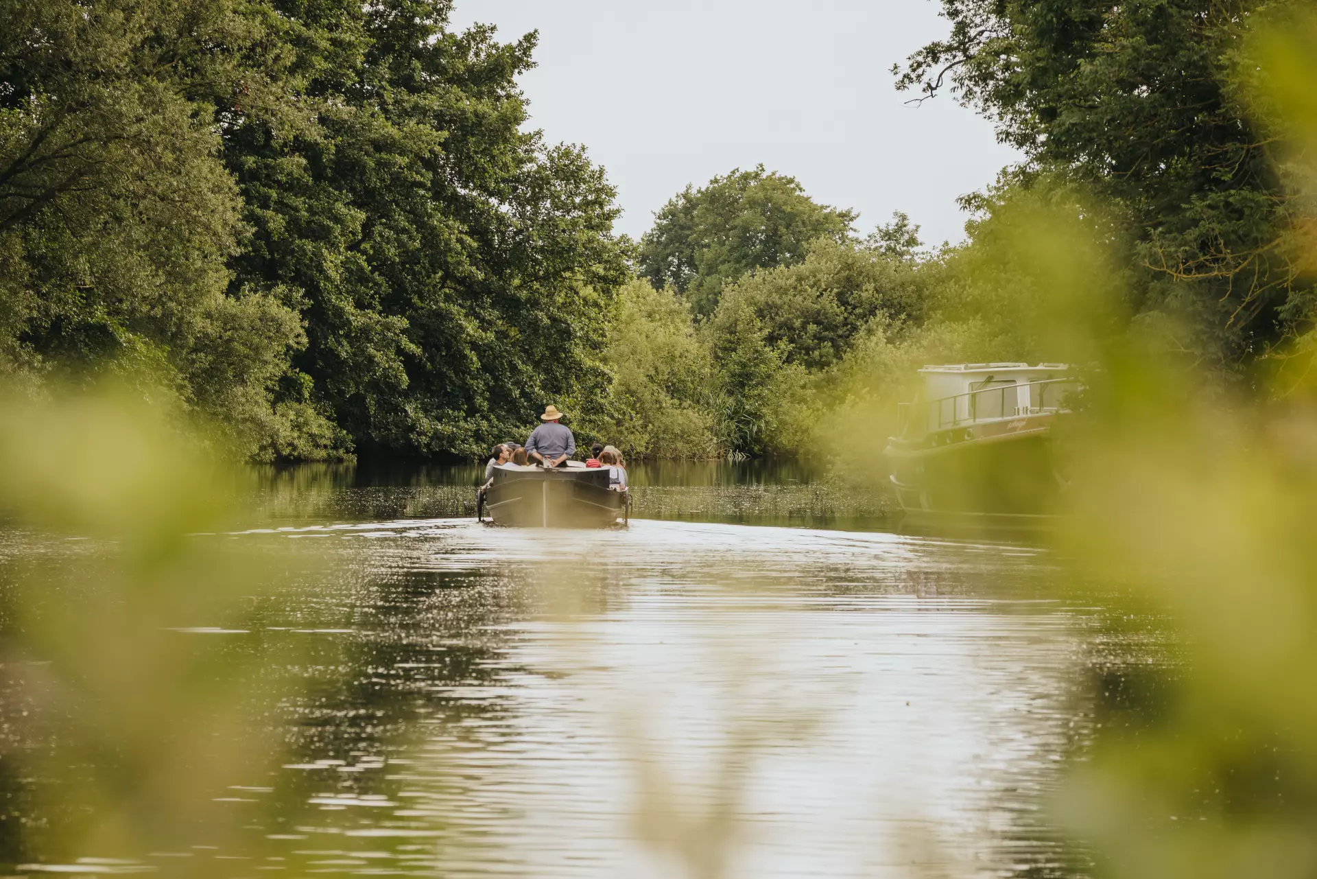 Bootsfahrt auf einem ruhigen Fluss in Worpswede mit dichter grüner Ufervegetation und Menschen im kleinen Boot