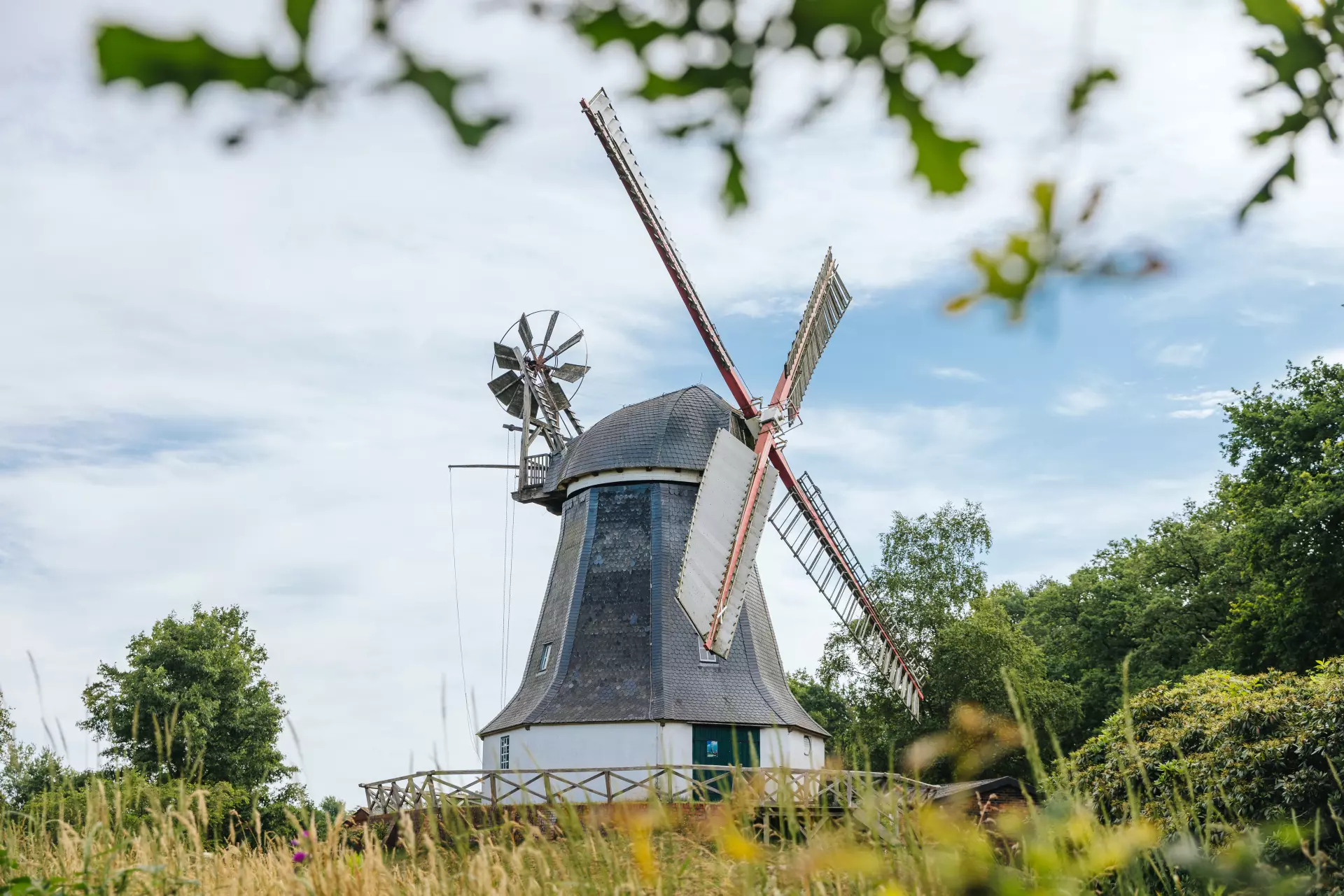 Historische Windmühle in Worpswede umgeben von Bäumen und Wiese unter bewölktem Himmel