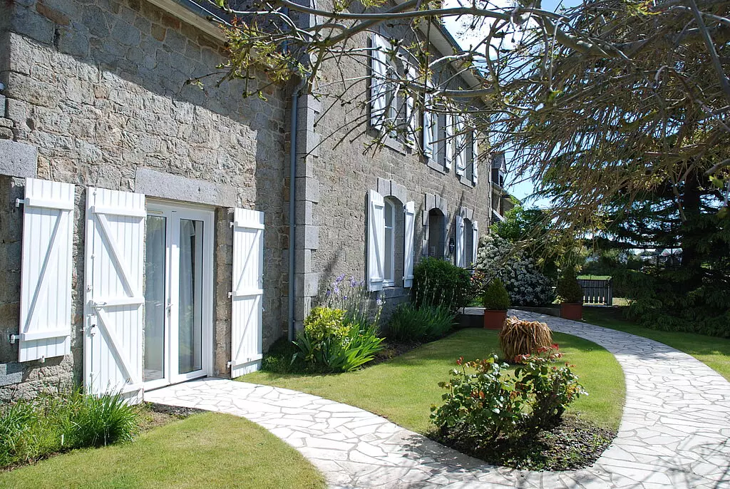 Das Hotel Le Chatteliert in Cancale. Foto: Gerd Ruhland Rustikales Steinhaus in Cancale mit weiß lackierten Fensterläden, Gartenwegen und üppigem Grün in der Bretagne