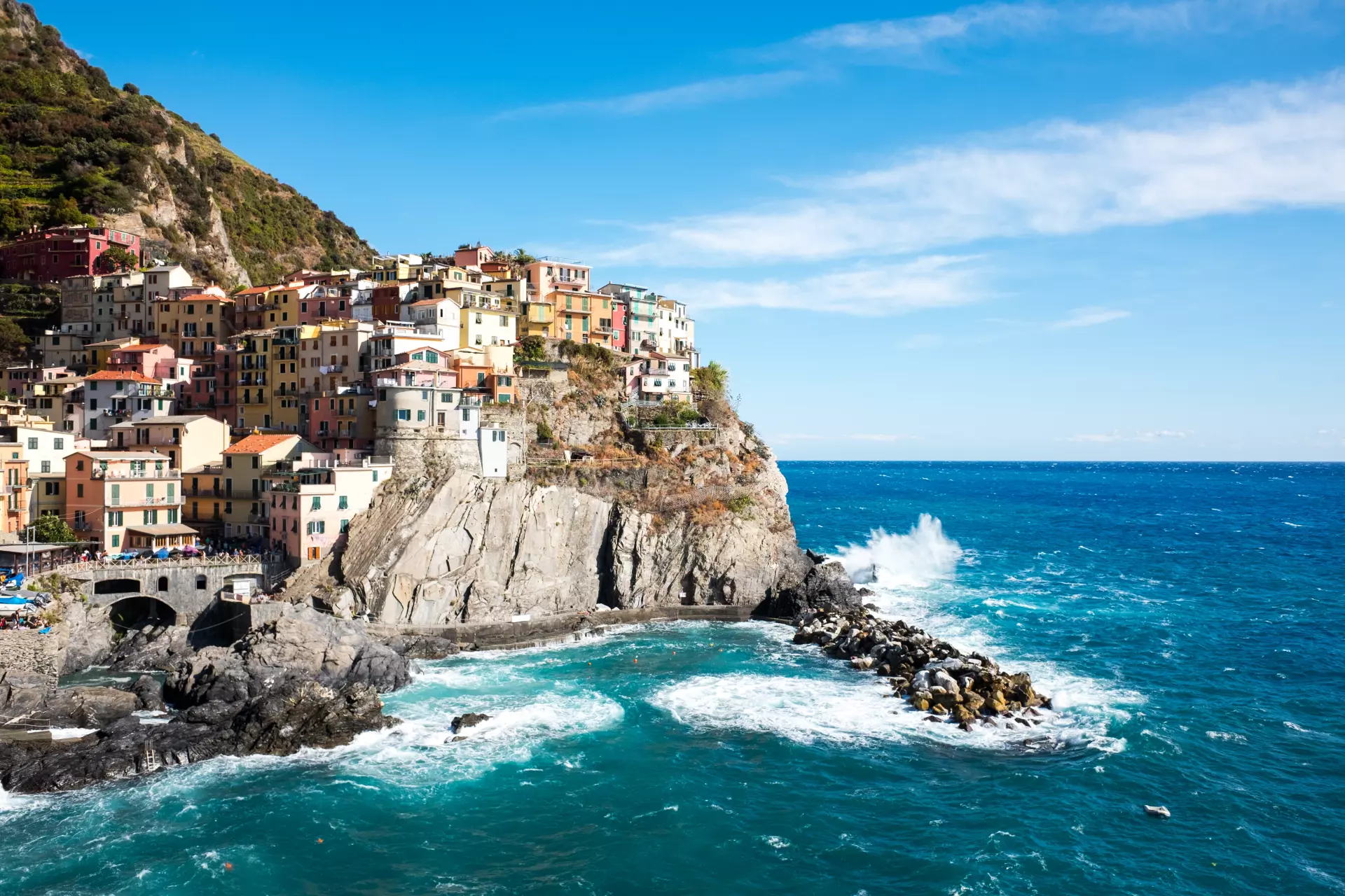 Bunte Häuser auf steilen Klippen über dem azurblauen Meer an der ligurischen Küste bei sonnigem Himmel