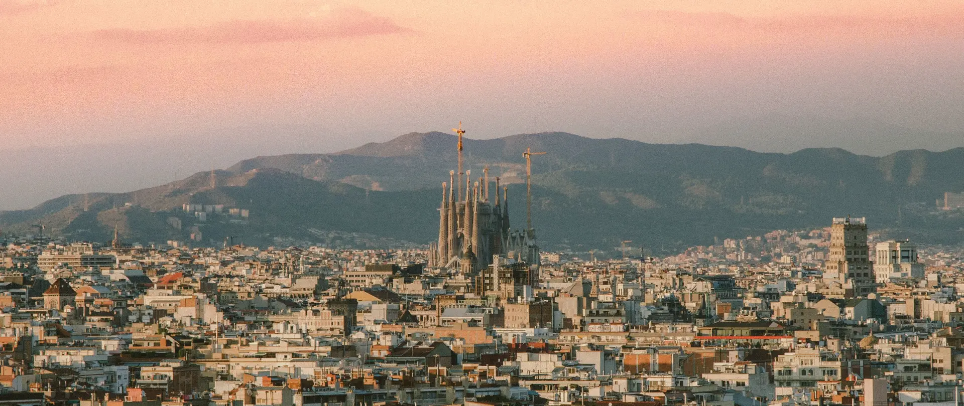 Skyline von Barcelona mit der Sagrada Família vor Bergen im warmen Abendlicht