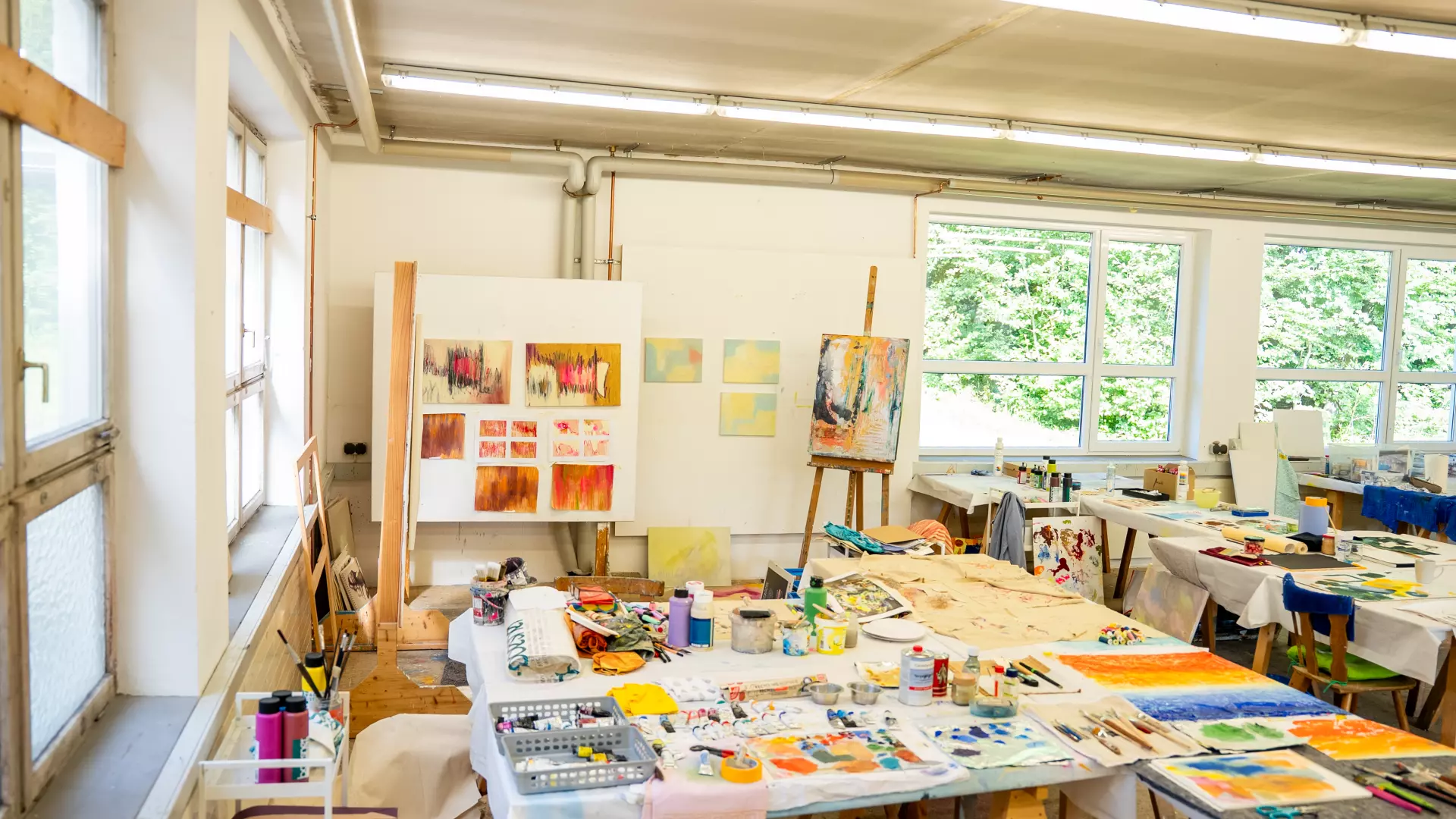 Das Atelier in der Kunstakademie Allgäu Großes helles Künstleratelier mit Staffeleien, Farbpaletten, Malutensilien und abstrakten Gemälden in der Kunstakademie Allgäu