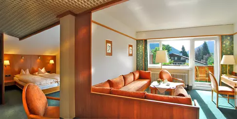 Wohnzimmer und Schlafzimmer im Steinbach-Hotel mit gemütlichen Möbeln, Balkon und Blick auf Berglandschaft im Berchtesgadener Land