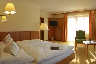 Gemütliches Hotelzimmer im Steinbach-Hotel mit Doppelbett, Sitzbereich, TV und großen Fenstern im Berchtesgadener Land