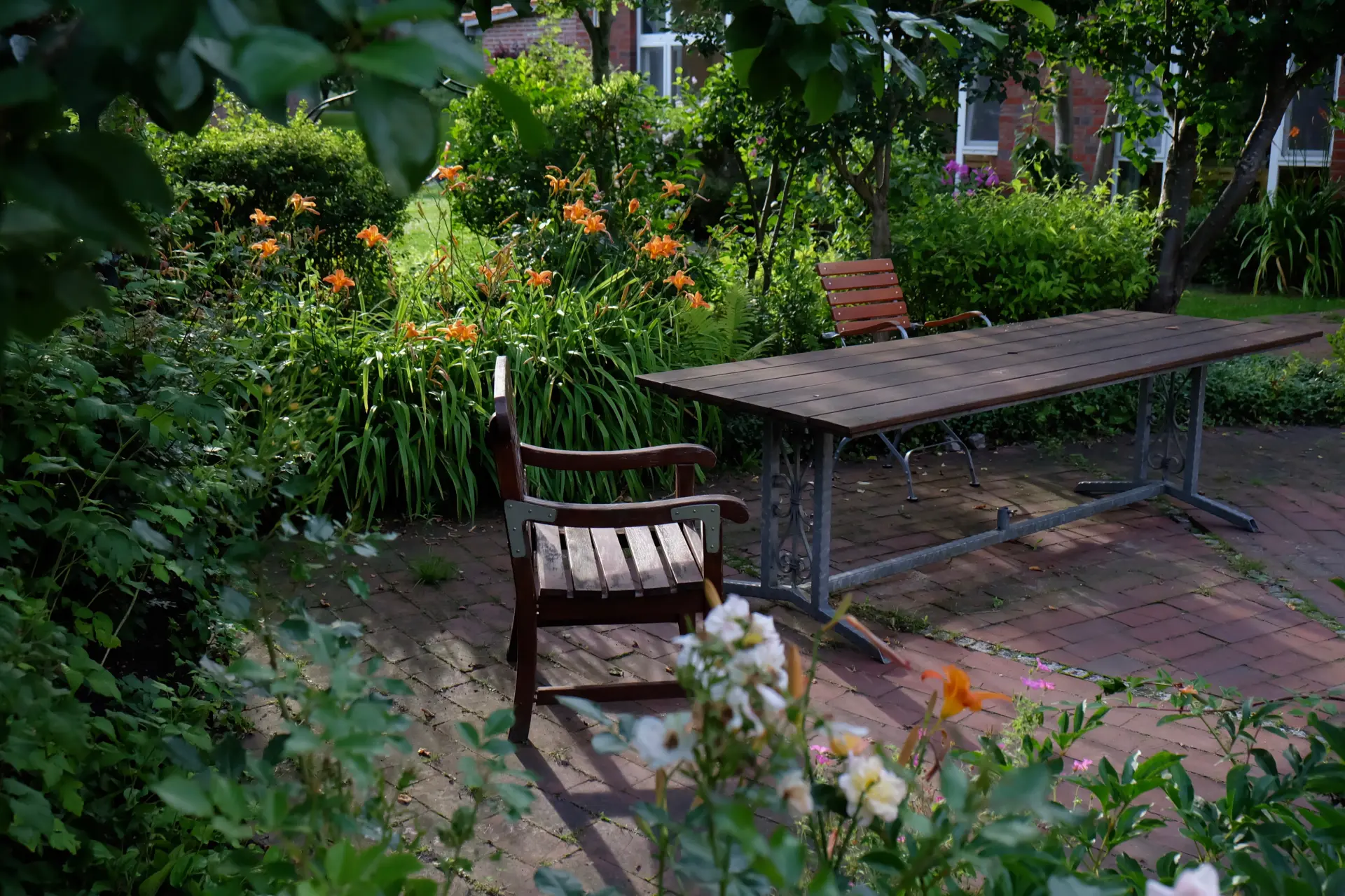 Hotel Kunze Hof Wattenmeer Jadebusen Außenbereich Gartenbereich im Seminarhotel Kunze-Hof mit Holzstühlen, großem Tisch und blühenden Blumen am Wattenmeer
