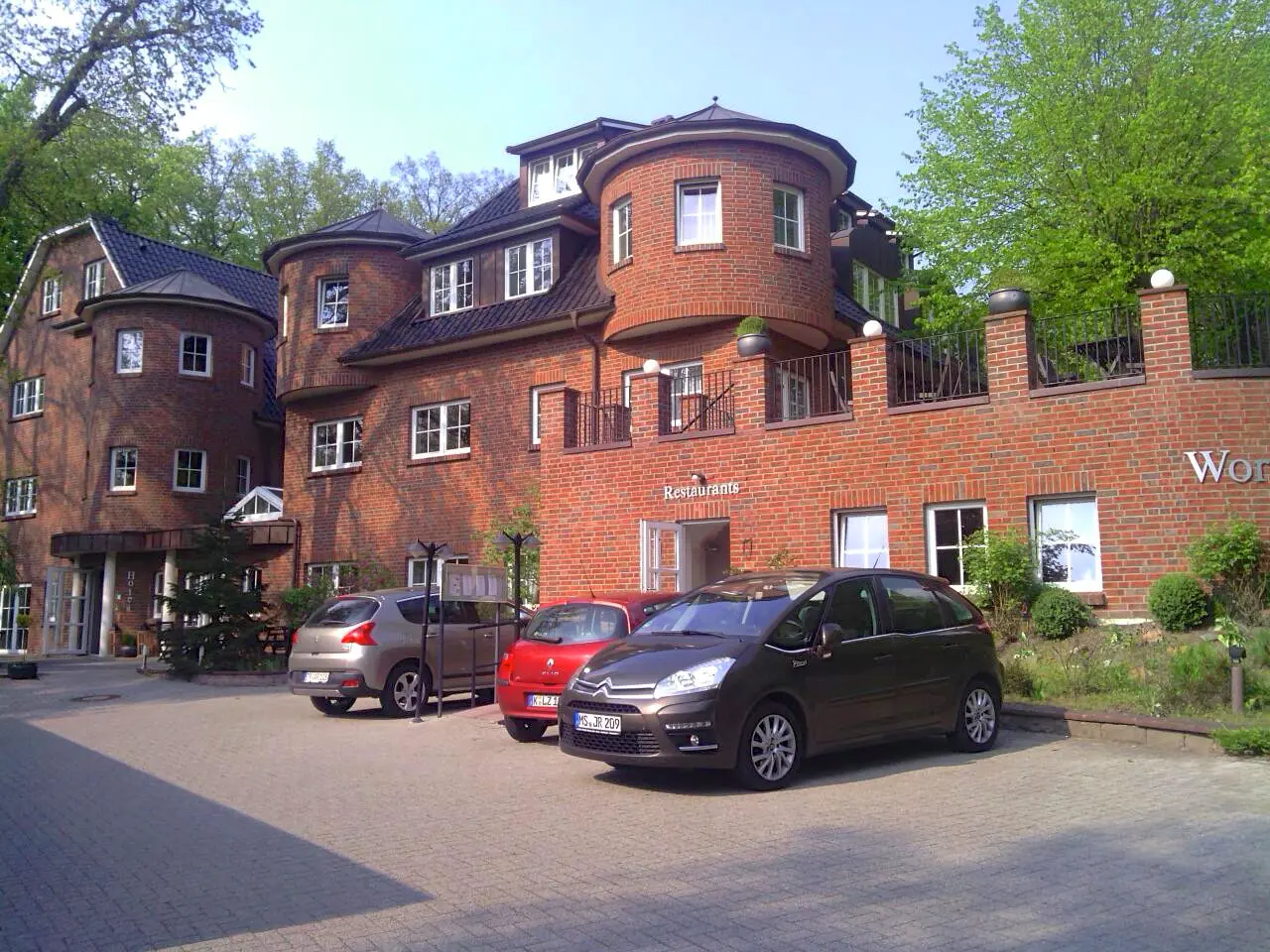 Hotel Worpswede Tor Rotes Backsteingebäude mit Türmen und drei geparkten Autos vor dem Hotel Worpsweder Tor in Worpswede an einem sonnigen Tag