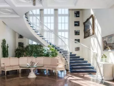 Spiraltreppe mit blauer Teppichauflage und Sitzecke mit Pflanzen im hellen Foyer des Kurhotels Sassnitz auf Rügen