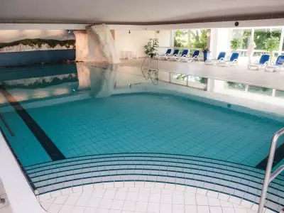 Hallenbad mit Wasserrutsche und Liegestühlen im Kurhotel Sassnitz auf Rügen