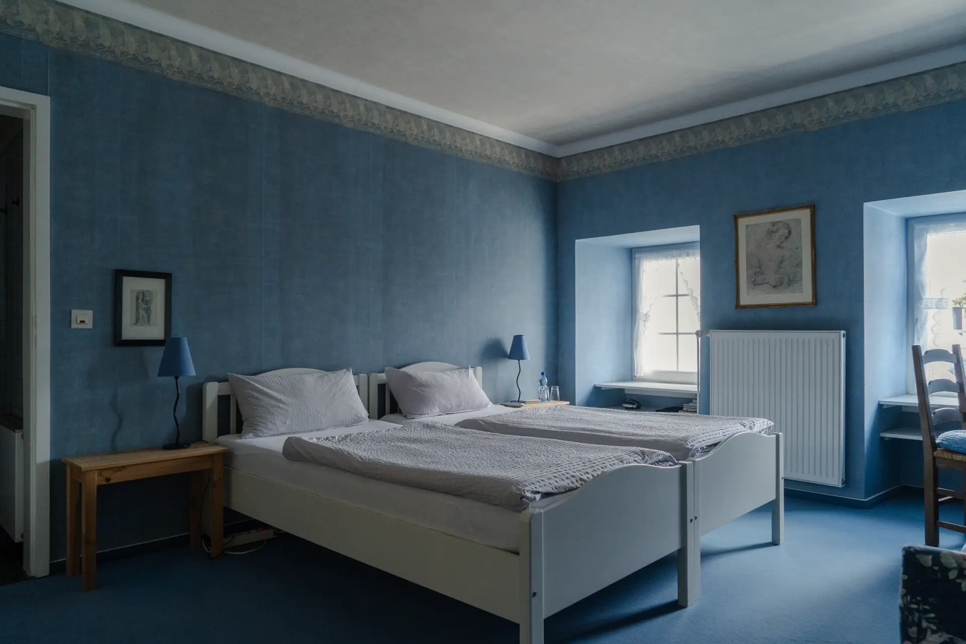 Hellblaues Schlafzimmer im Landhaus Arnoth mit zwei Einzelbetten, Holzmöbeln und Fenstern mit Blick auf die Moselregion