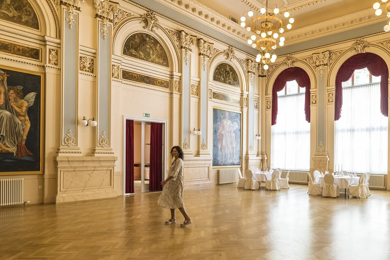 Prächtiger Ballsaal im Parkhotel Bad Schandau mit hohen Fenstern, großen Gemälden und elegantem Parkettboden