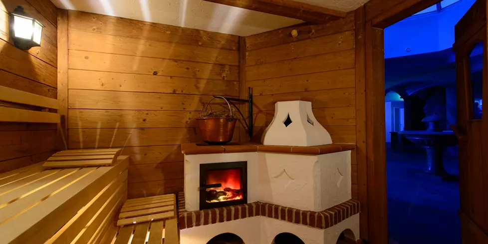 Sauna mit Holzverkleidung und beheiztem Kamin im Steinbach-Hotel im Berchtesgadener Land