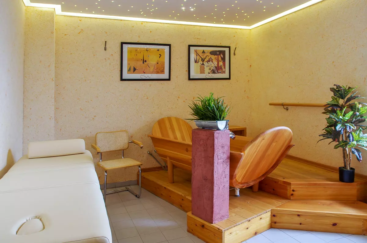 Ruhebereich im Hotel Birschel-Mühle in Hattingen mit Holzliegen, Pflanzen, Deckenbeleuchtung und zwei Wandbildern