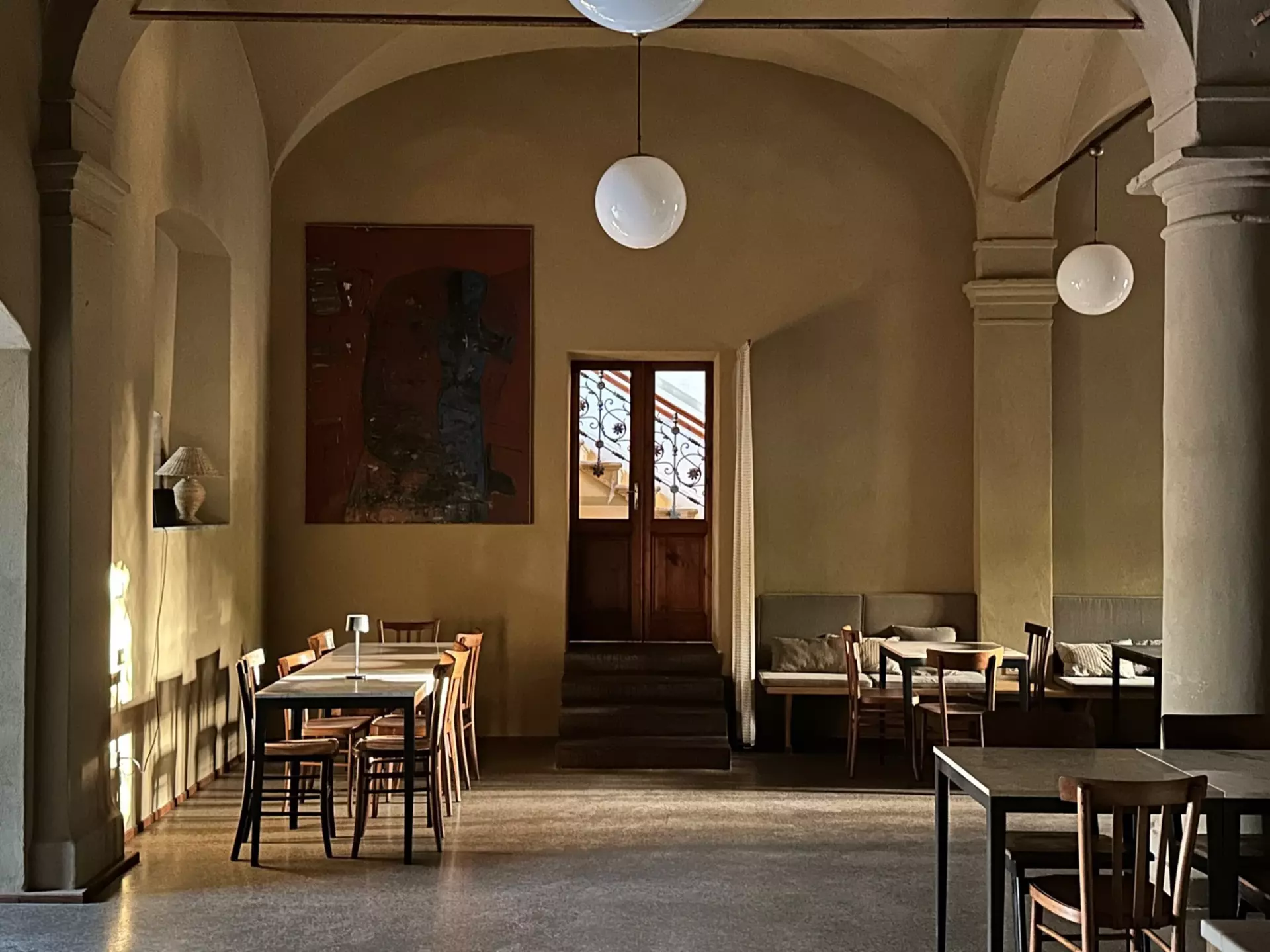 Lounge 2 Innenraum einer Unterkunft in Toskana mit Tischen, Stühlen, Säulen und warmem Licht in historischem Ambiente