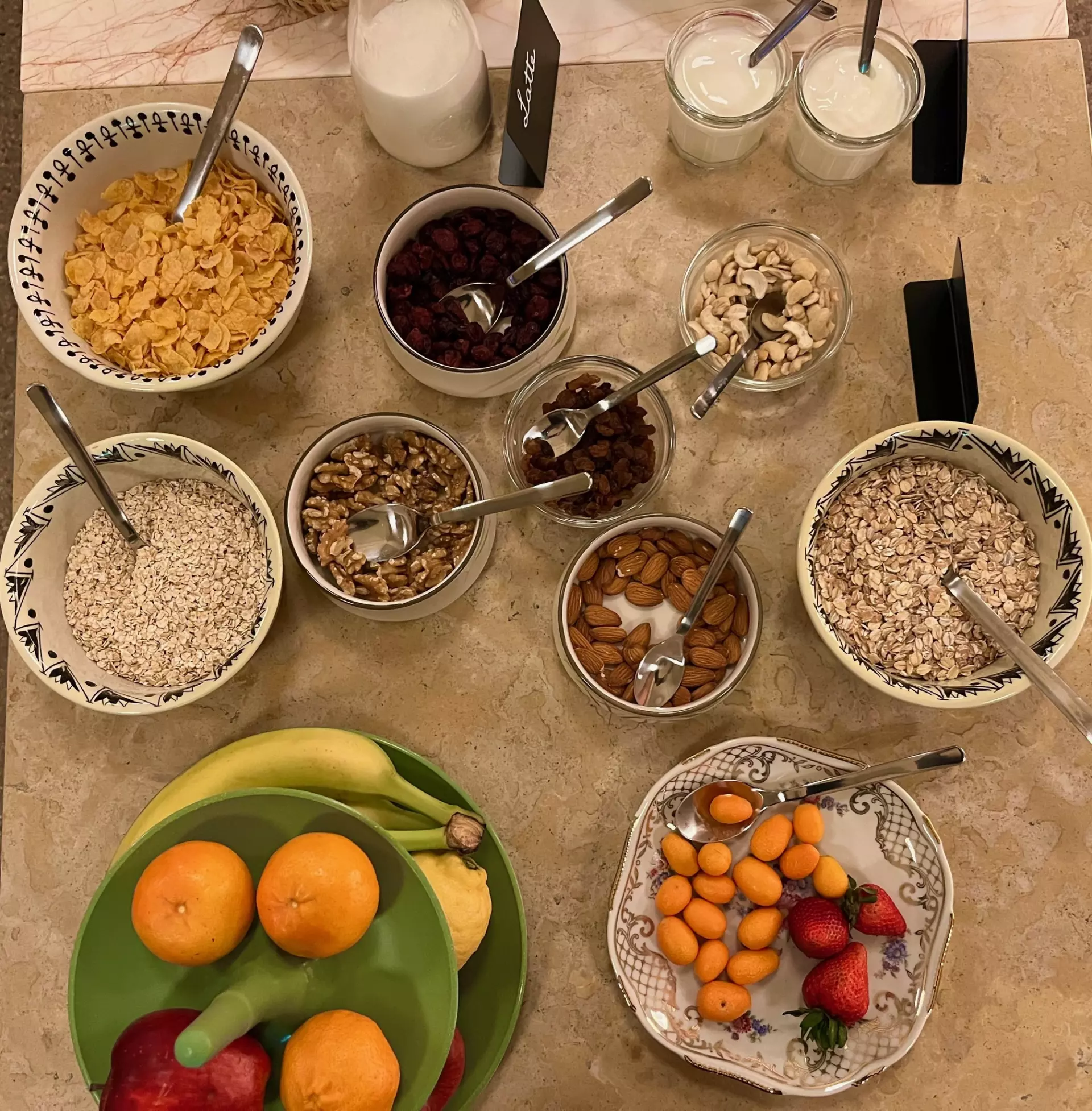 Verschiedene Frühstückszutaten wie Cornflakes, Haferflocken, Nüsse, Trockenfrüchte, Joghurt und frisches Obst auf einem Tisch in der Unterkunft Toskana