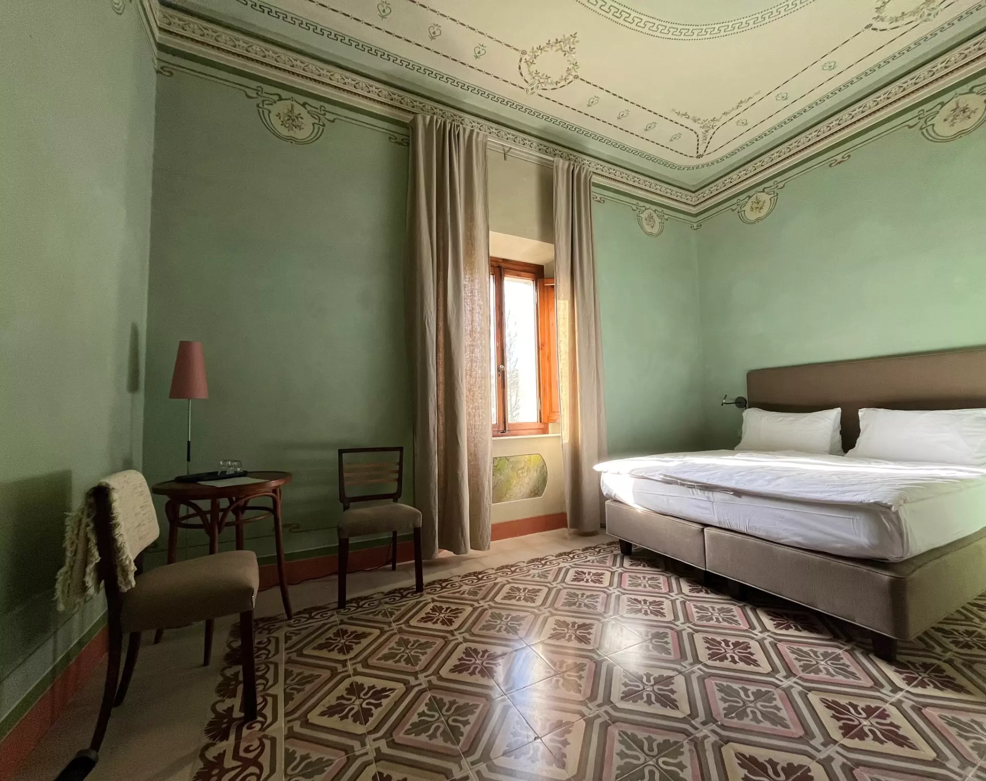 Doppelzimmer Elegantes Schlafzimmer mit grünem Stuck, verziertem Deckenspiegel, Doppelbett, antiken Stühlen, kleinem Tisch und gemustertem Boden in Unterkunft Toskana