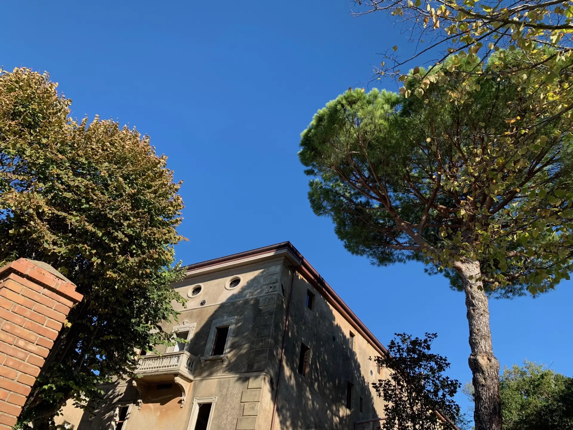 B&B Außenansicht Altes toskanisches Gebäude mit Balkon, umgeben von Bäumen unter klarem blauem Himmel, in der Unterkunft Toskana