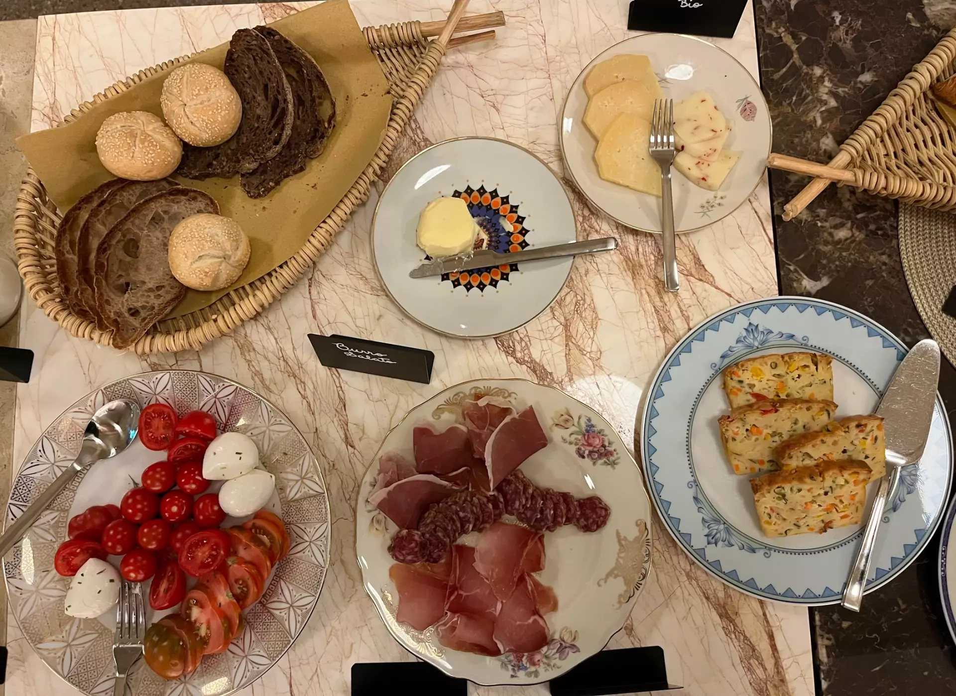 Vielfältige Vorspeisen mit frischem Brot, Käse, Tomaten, Mozzarella und Aufschnitt auf einem gedeckten Marmortisch in der Unterkunft Toskana