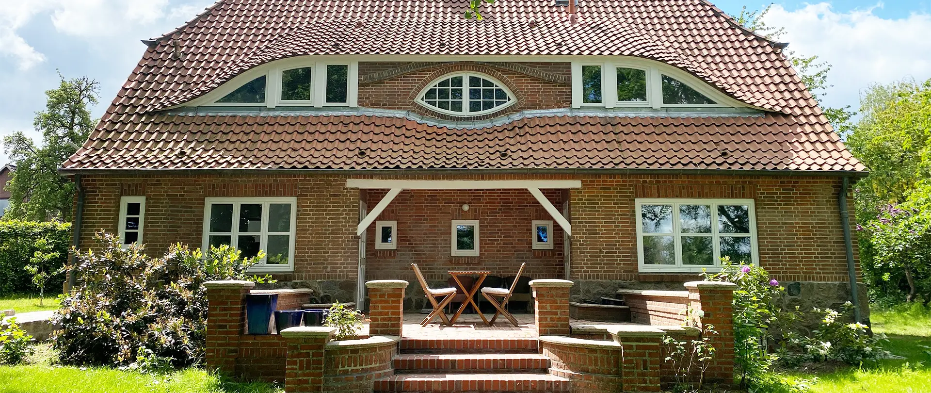 werkgut atelierhaus terrasse Backsteinhaus mit geschwungenem Dach und Terrasse mit Gartenmöbeln im Atelier im Werkgut im Naturpark Aukrug