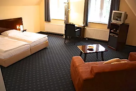 Hotelzimmer im Hotel Worpsweder Tor mit zwei Einzelbetten, Schreibtisch, Fernseher, Sofa und Teppichboden in Worpswede