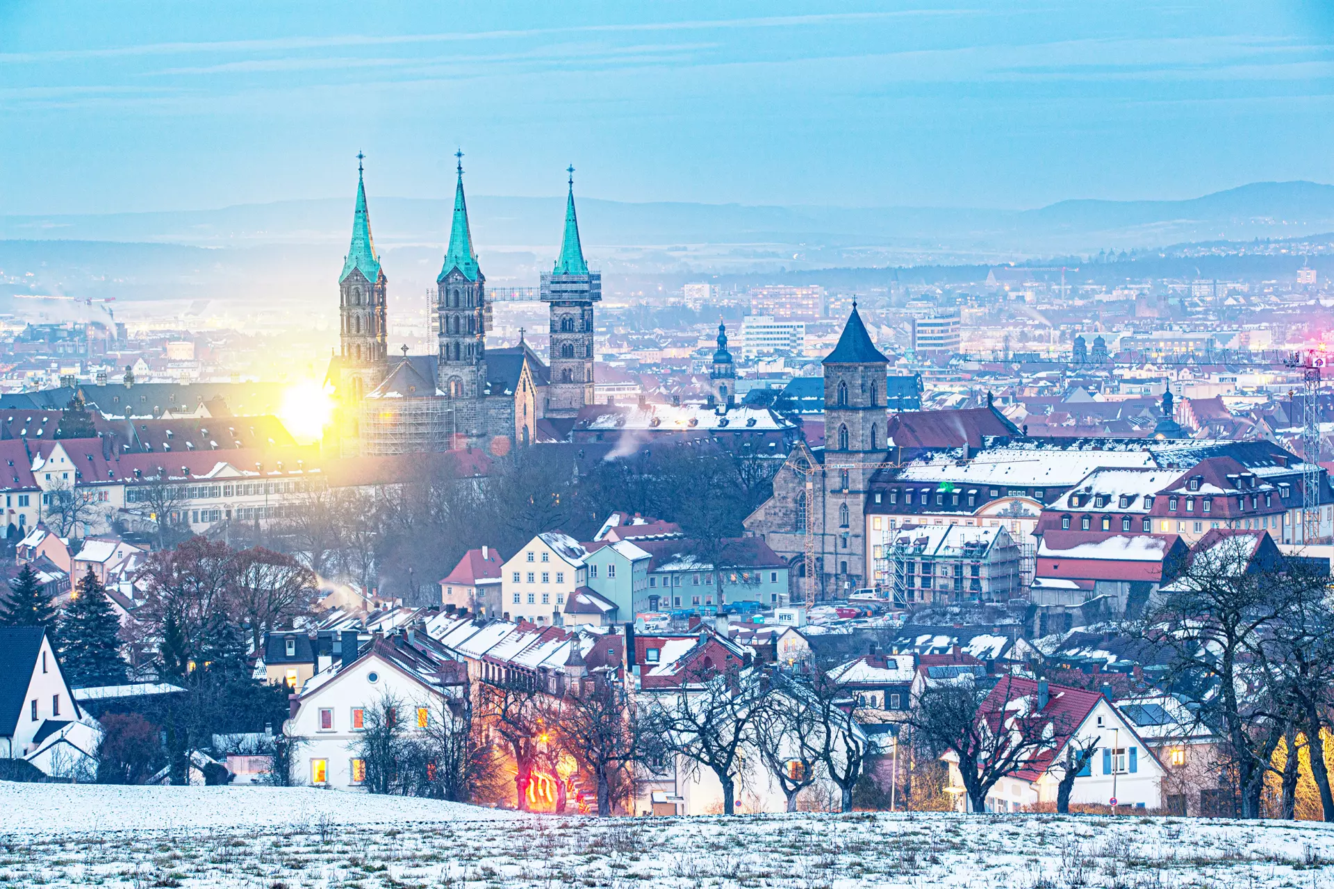 Morgendämmerung über den Dächern Blick über eine Stadt mit Kirchtürmen bei Sonnenaufgang – atmosphärische Stadtansicht von artistravel Fotografie Dozent Björn Göttlicher