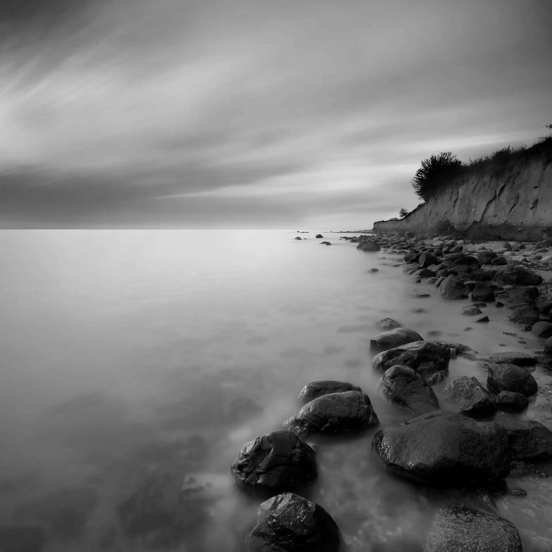 Stimmungsvolle Schwarz-Weiß-Fotografie am Wasser Schwarz-Weiß-Landschaft mit Wasser, Sand und Wolken – minimalistisch komponiert von artistravel Dozent Thomas Bichler