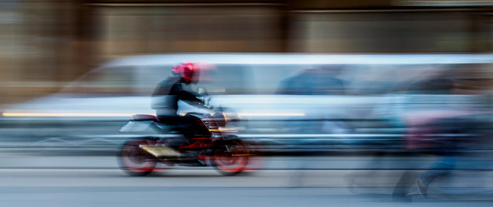 Holger Michlenz zeigt mit Langzeitbelichtung einen Motorradfahrer in schneller Bewegung vor verschwommenem urbanem Hintergrund